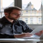 Male IT professional in Austria Vienna office reviewing XML e-invoice software on laptop, professional corporate setting